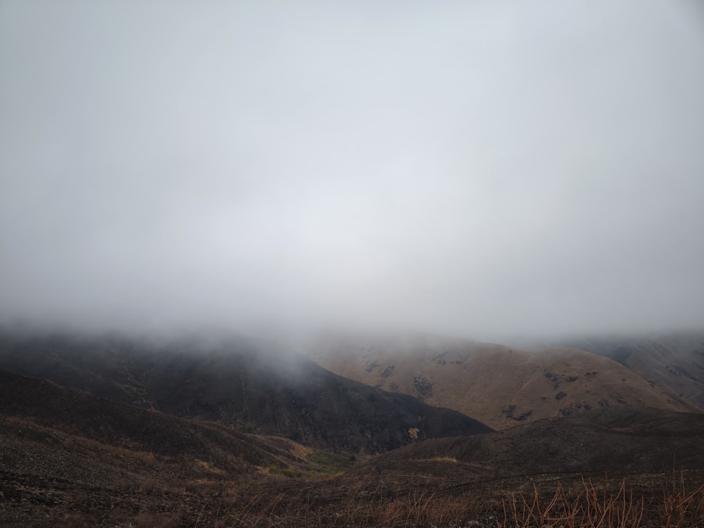 a foggy landscape with mountains in the distance