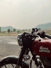 Close-up of a Royal Enfield Bullet 350 parked on rugged terrain with a dark, moody background.