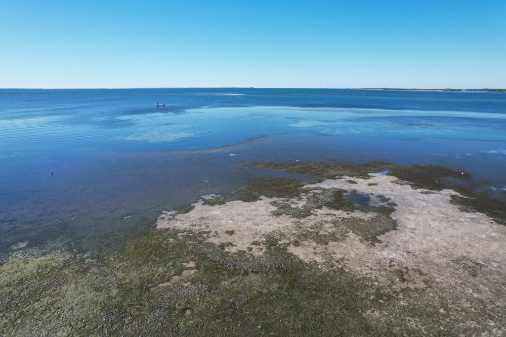 an aerial view of a body of water with a boat in the distance