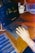 A hand is placed on the keyboard of a laptop displaying photo editing software. There is a mug and some film strips on a wooden table, along with a charger connected to the laptop.