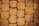 A close-up view of a textured stone pavement. The stones are rectangular and laid out in a neat pattern. The surface appears rough and porous, suggesting wear and natural erosion over time. The color is a warm beige, adding a rustic vibe.
