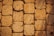 A close-up view of a textured stone pavement. The stones are rectangular and laid out in a neat pattern. The surface appears rough and porous, suggesting wear and natural erosion over time. The color is a warm beige, adding a rustic vibe.