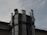 Several metallic ventilation ducts are attached to the exterior of a building, extending vertically. The sky in the background is overcast, and there are cables running across the scene.