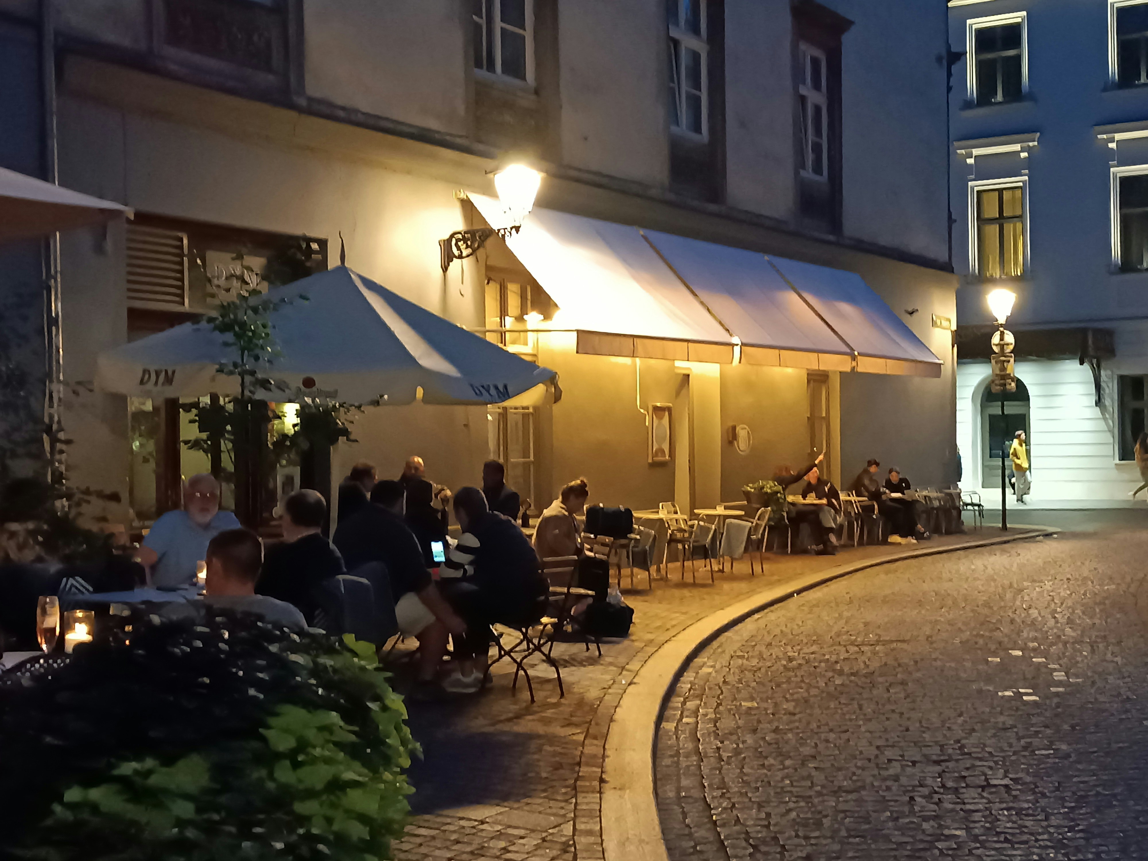 a group of people sitting outside of a restaurant at night