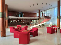 a lobby with red chairs and a spiral staircase