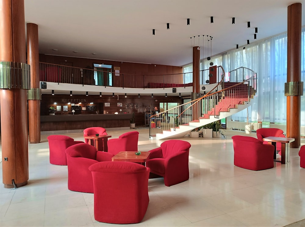 a lobby with red chairs and a spiral staircase