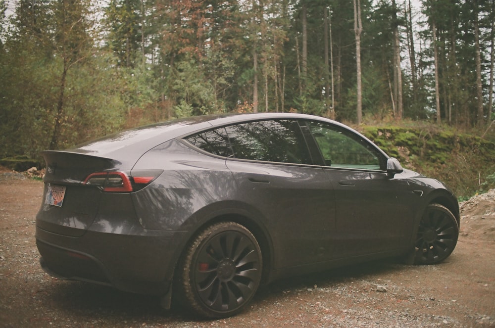 a car parked on a dirt road in front of a forest