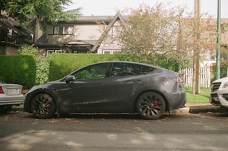 Electric car driving smoothly through a green city street with trees and modern buildings.