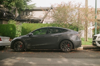 Electric car driving smoothly through a green city street with trees and modern buildings.