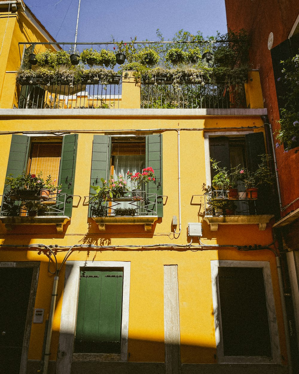 a yellow building with green shutters and a green door