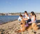 A happy family enjoying a sunny day on the beach with their dog playing nearby.