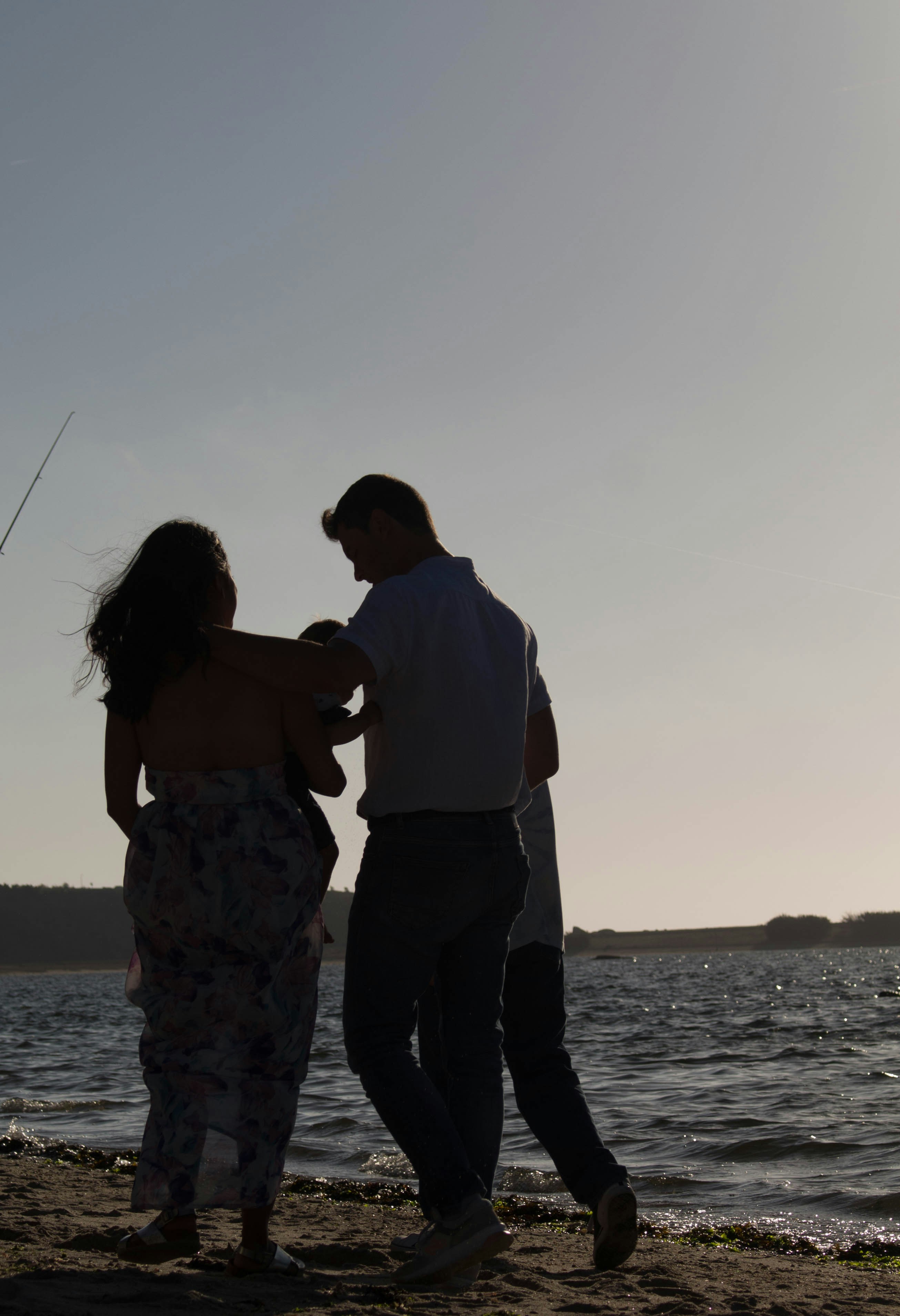 a man and a woman standing on a beach next to a body of water