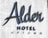 Large, stylish lettering spells out 'Alder Hotel Uptown' on a textured, light-colored wall. The design features a mix of elegant cursive and bold uppercase fonts, creating a modern and sophisticated look.