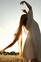 A model wearing a modern, flowing dress standing in natural sunlight.