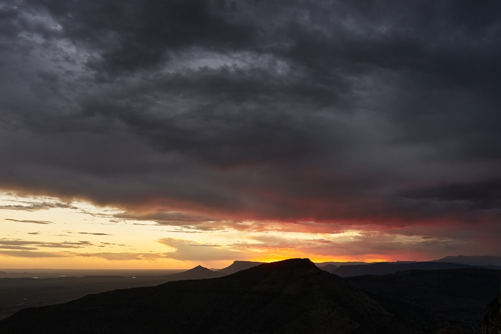 the sun is setting over a mountain range