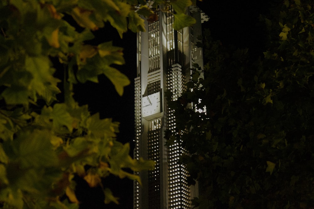 una alta torre de reloj que se eleva sobre una ciudad por la noche