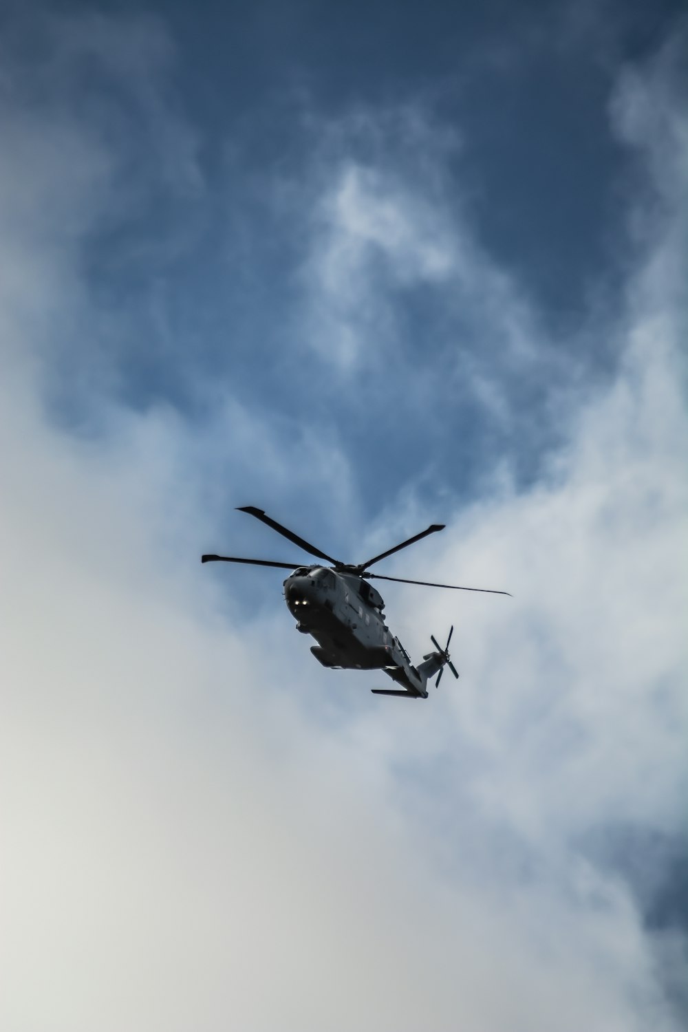 a helicopter flying through a cloudy blue sky