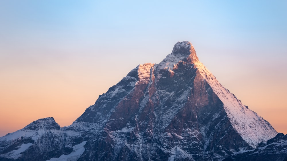 a very tall snow covered mountain with a sky background