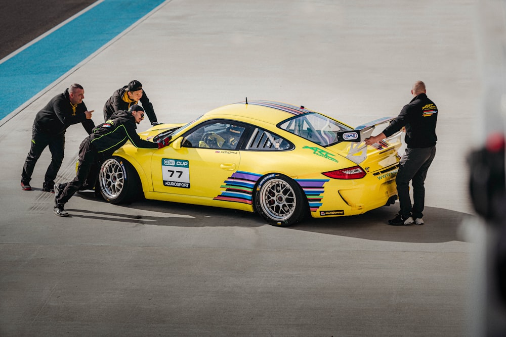 a group of people standing around a yellow car