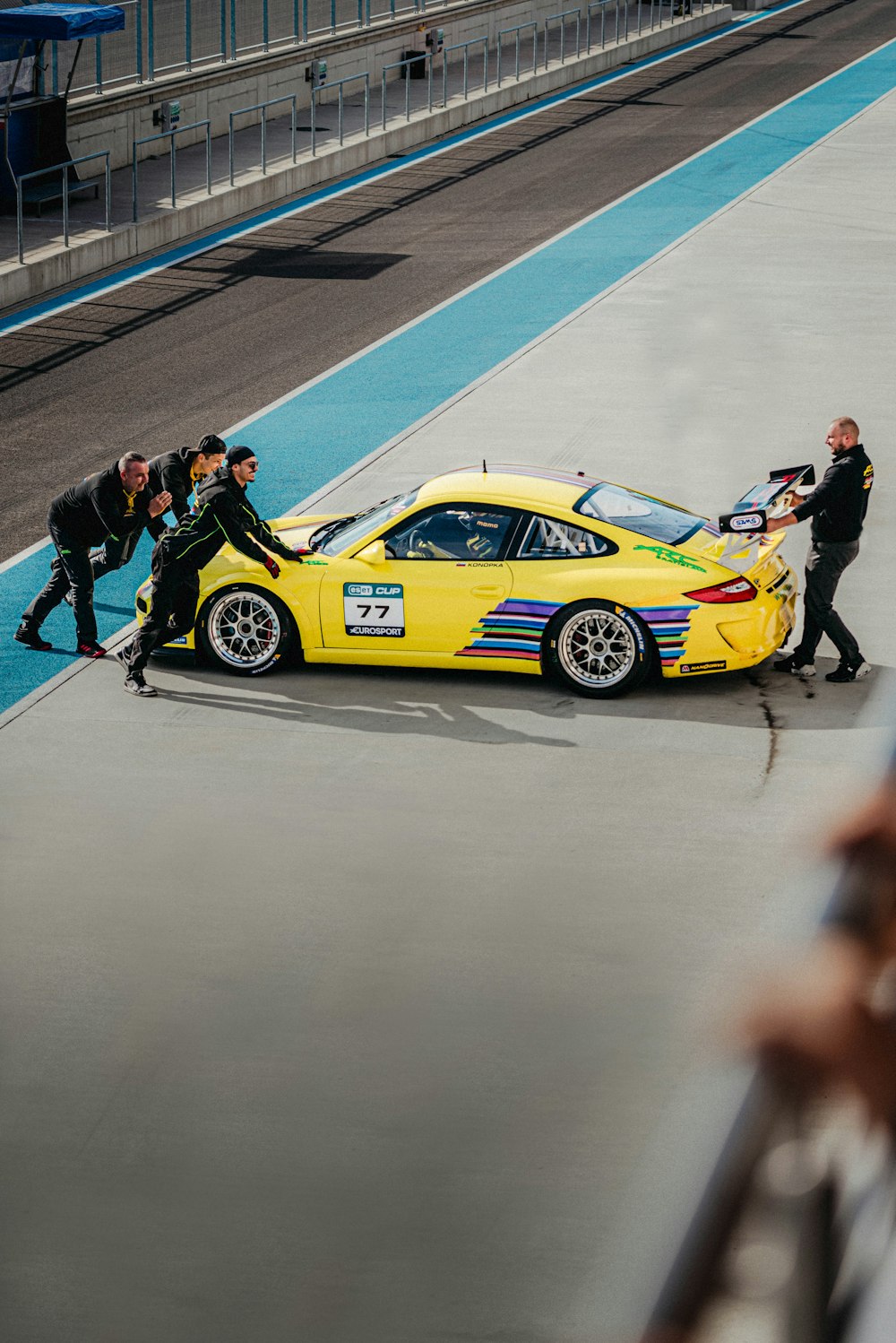 a group of people standing around a yellow car