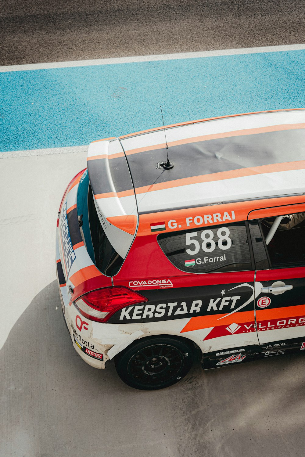 a red and white car driving down a race track