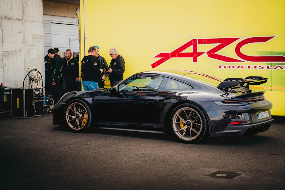 a black sports car parked in front of a yellow wall