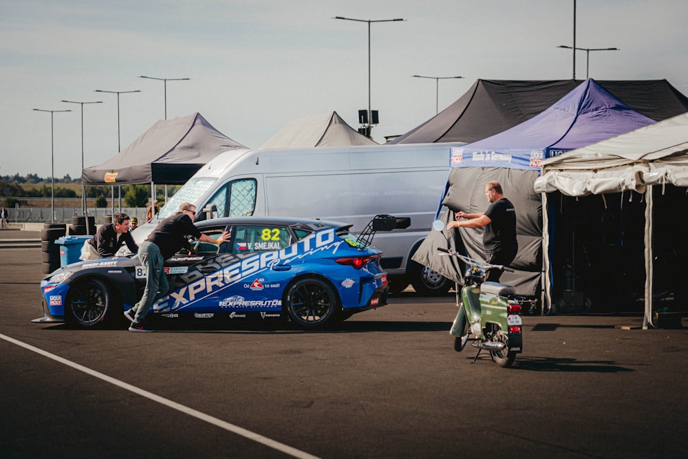 a car is parked in a parking lot next to tents