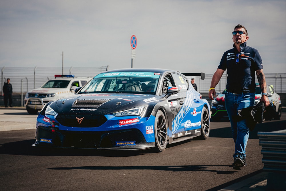 a man walking next to a blue sports car