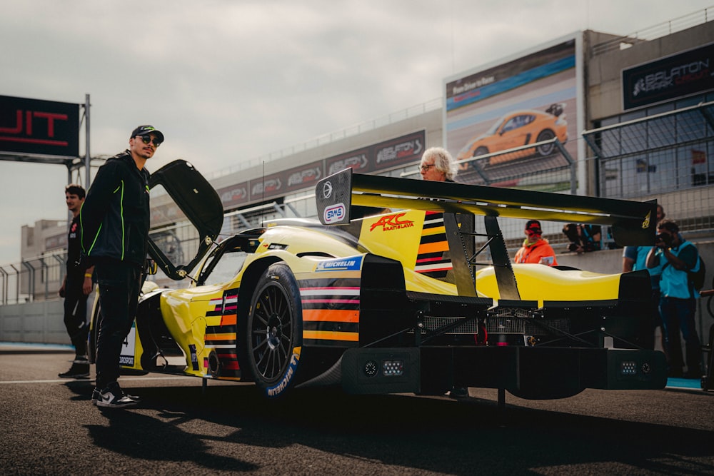 a man standing next to a yellow race car