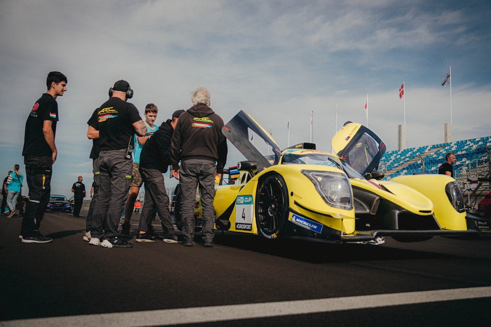 a group of men standing around a yellow race car