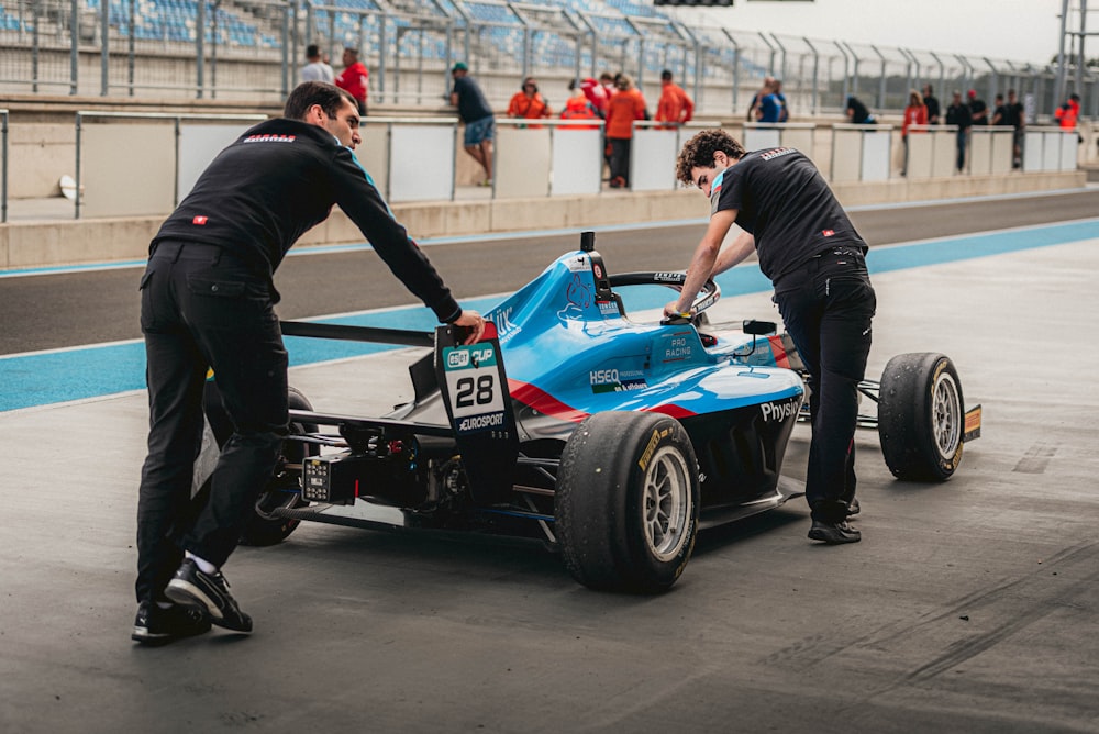 two men working on a race car on a track