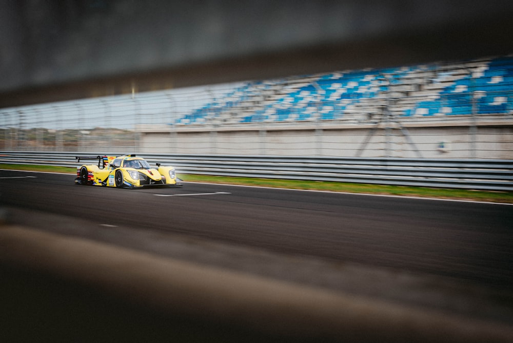 a yellow race car driving down a race track