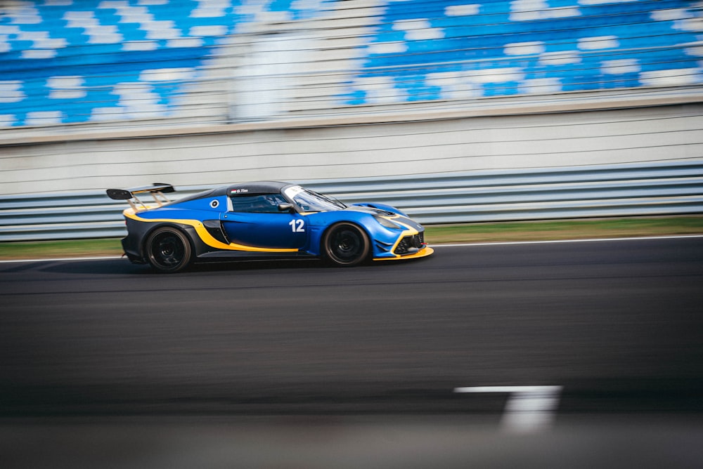 a blue and yellow sports car driving down a race track