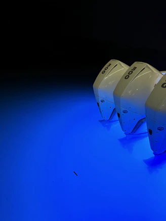 Sleek display of premium outboard engines illuminated by blue and white lighting in a modern showroom.