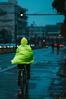 A Lumina Apparel windbreaker catching the light as the wearer rides a bike through city streets.