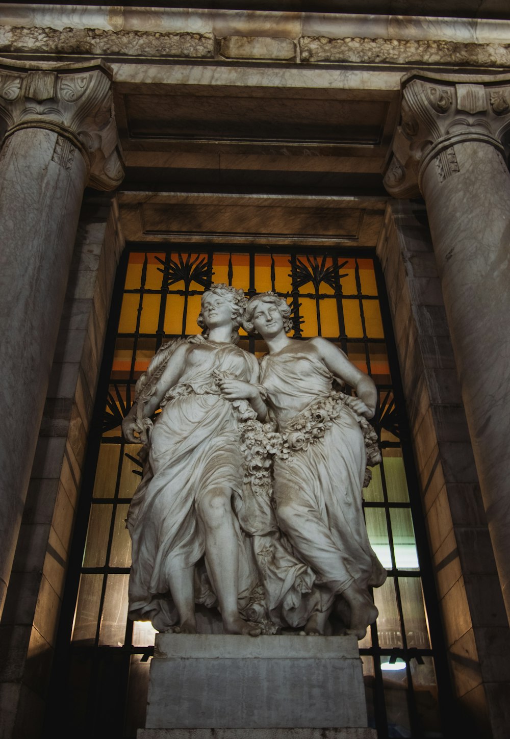 a statue of two women in front of a stained glass window