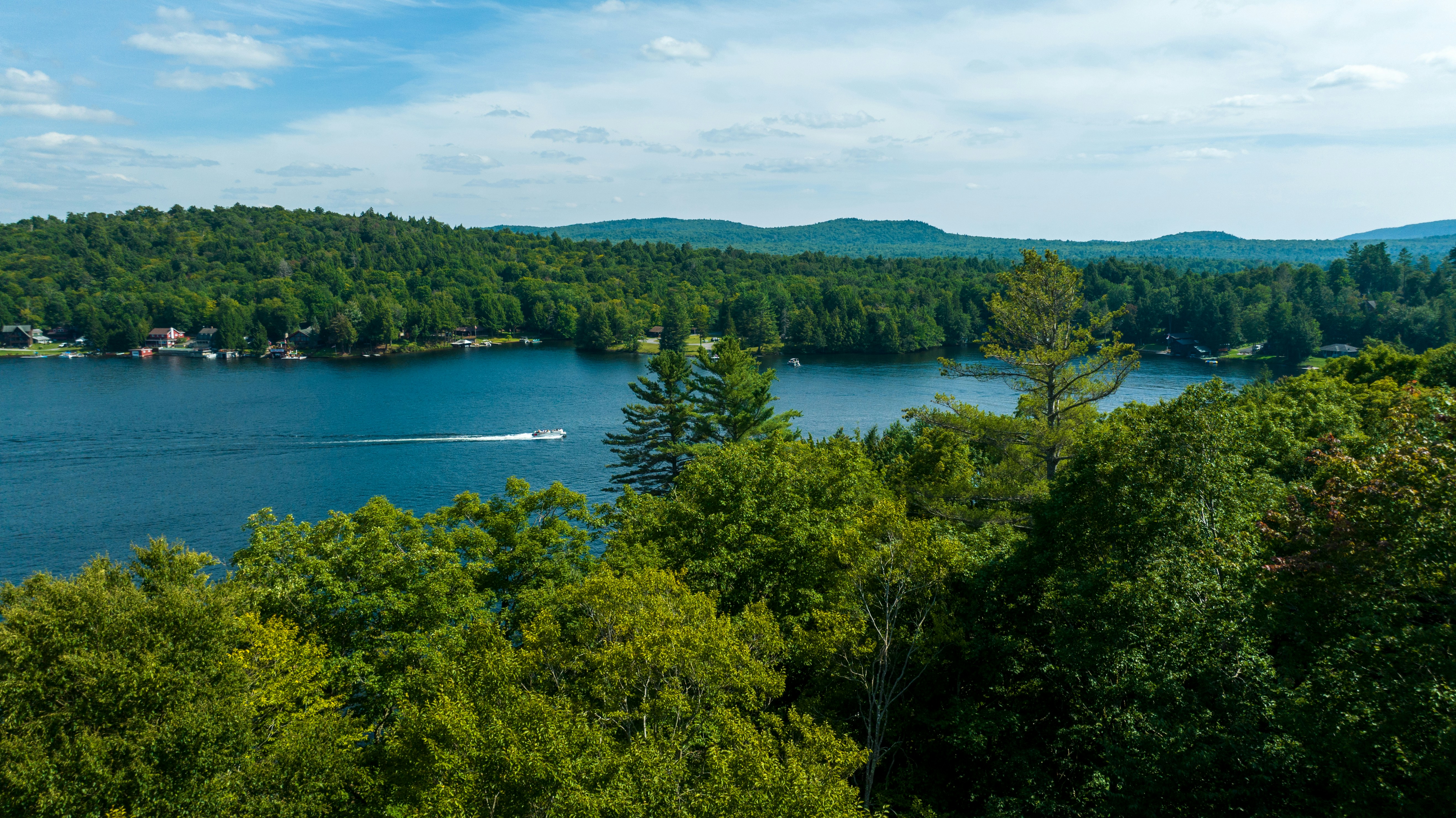 a lake surrounded by trees with a boat in the water