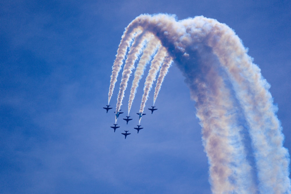 a group of jets flying through a blue sky