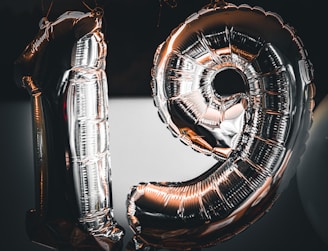 Close-up of shiny number-shaped balloons glowing under party lights.