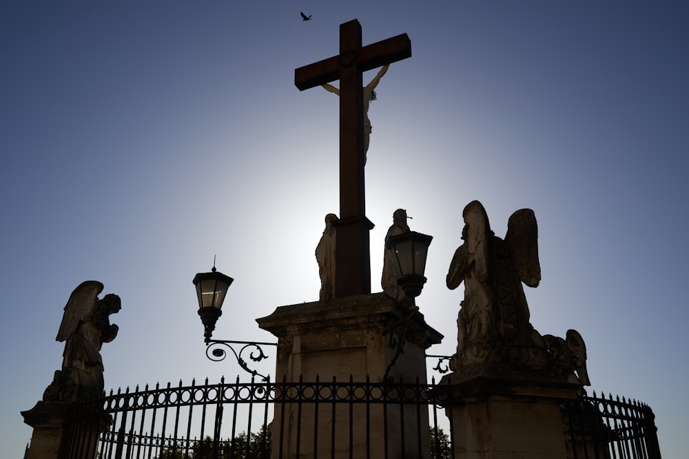 a cross on top of a building with statues around it