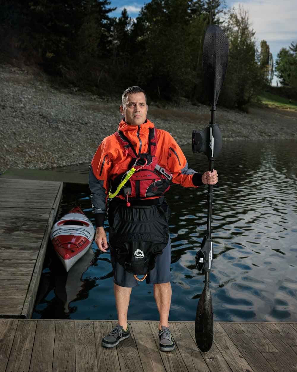 a man standing on a dock holding a kayak