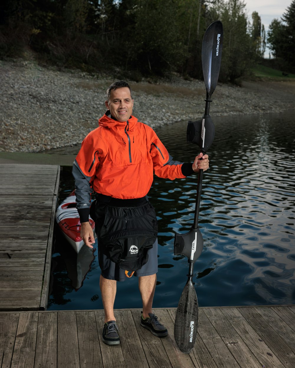 a man standing on a dock holding a paddle