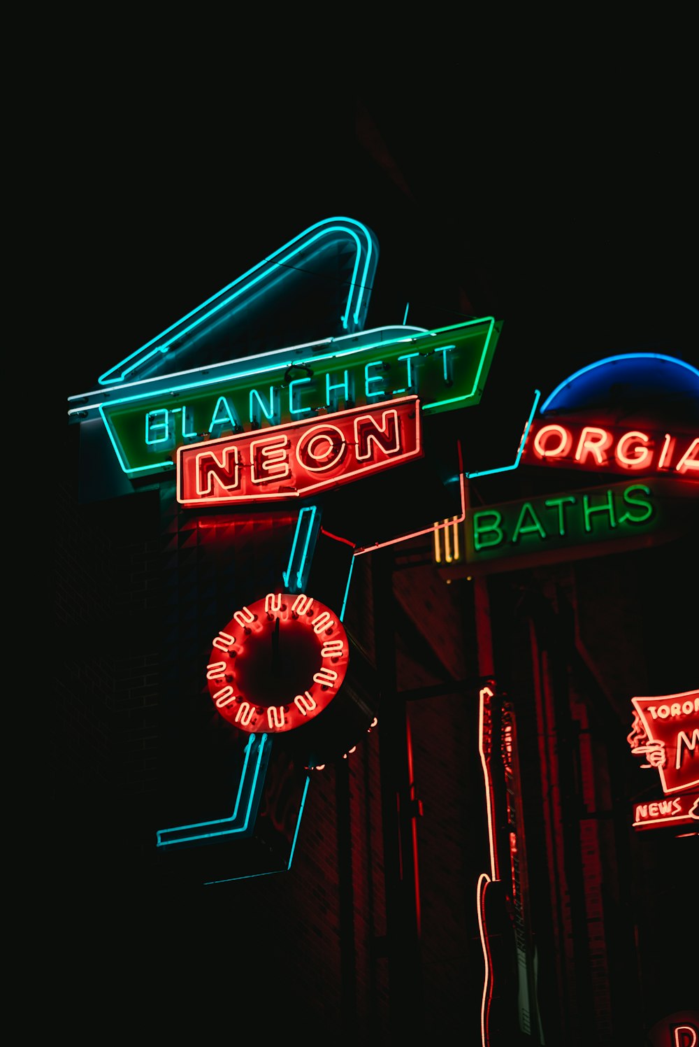 a bunch of neon signs that are on the side of a building