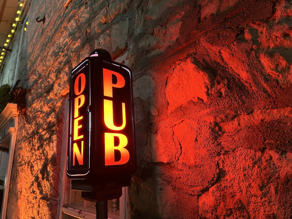 a pub sign lit up against a stone wall