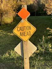 A yellow caution sign glowing softly under a protective umbrella, symbolizing alert and care.