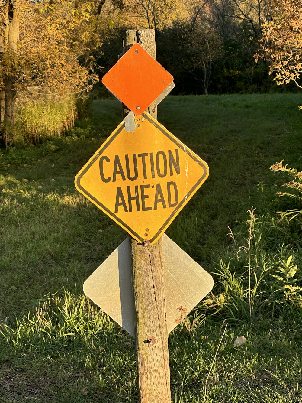 a caution sign on a wooden post in the grass