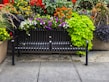 Sleek metal frame patio bench surrounded by blooming garden flowers
