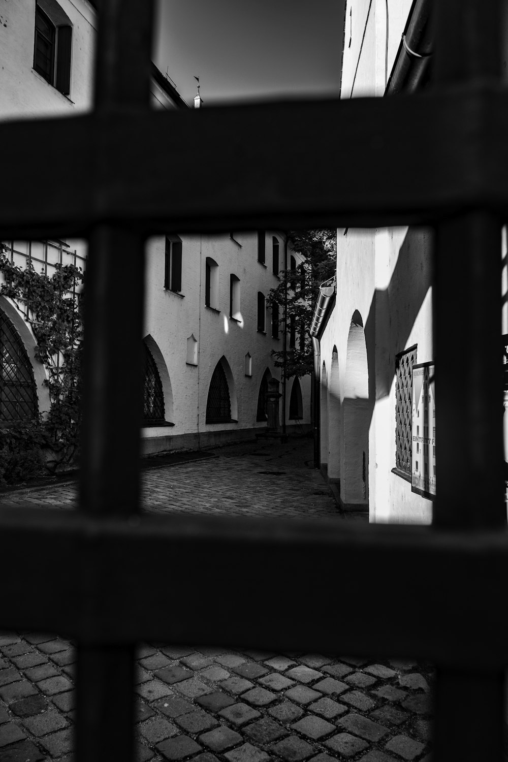 a black and white photo of a building through a fence