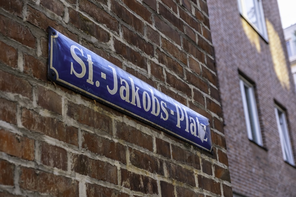 a blue street sign mounted to a brick wall