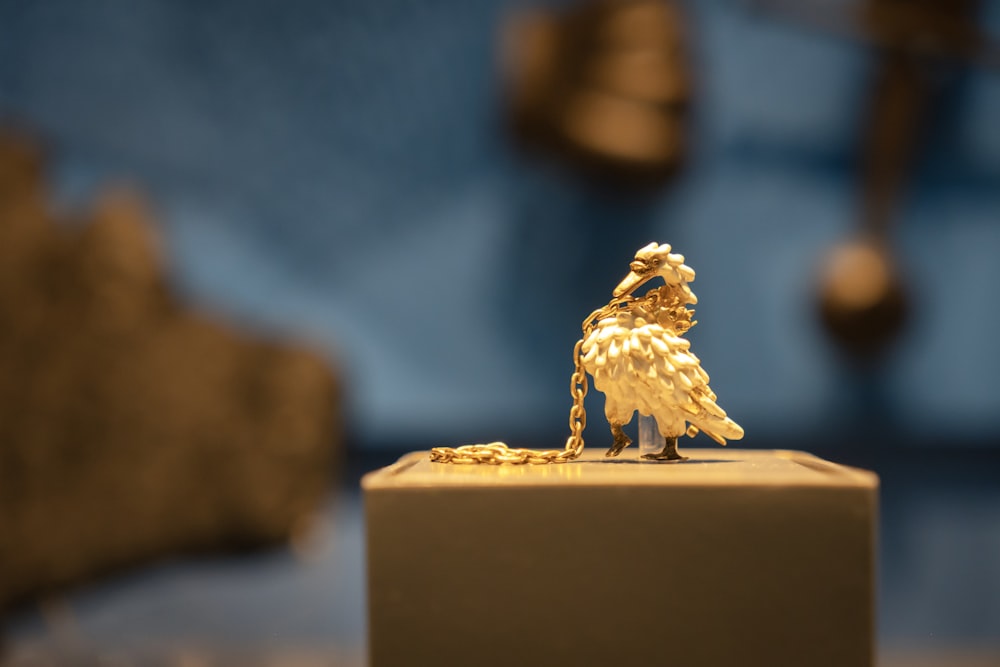 a gold figurine of a bird on a stand